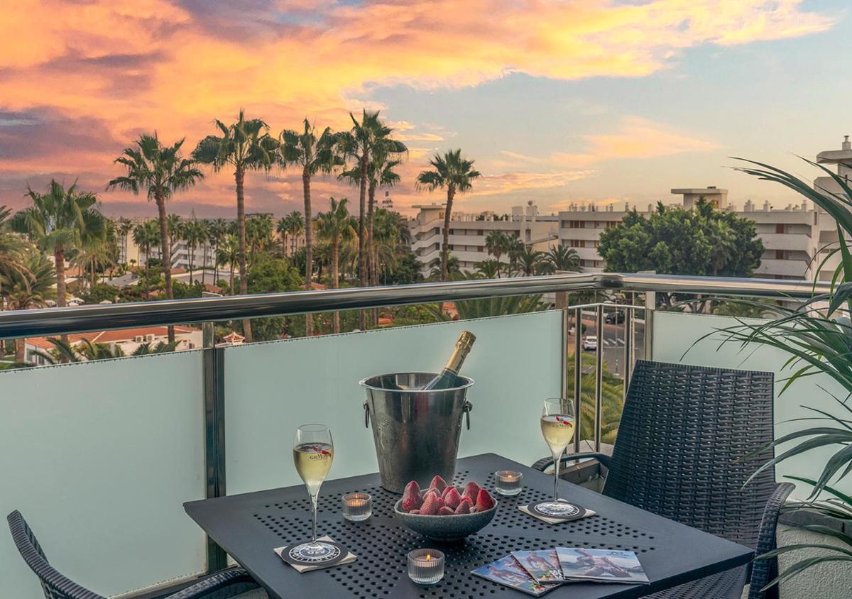 una mesa con un bol de frutas y copas de vino en el balcón en Axel Beach Maspalomas - Adults Only, en Playa del Inglés