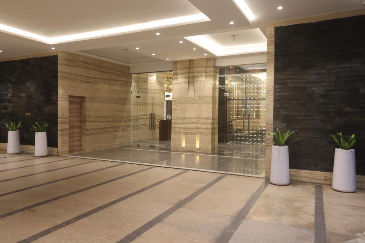 a lobby with three potted plants in a building at Pharos Hotels in Chennai