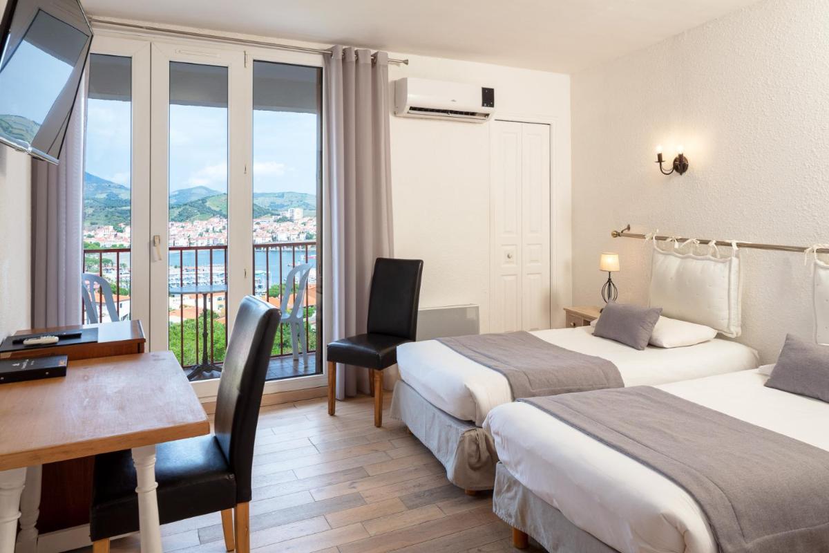 une chambre d'hôtel avec deux lits, un bureau et une fenêtre dans l'établissement Le Catalan, à Banyuls-sur-Mer