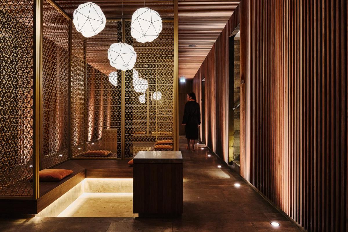 Ein Mann, der mit einem Tisch und Lichtern den Flur entlang geht. in der Unterkunft Spa & Resort Bachmair Weissach, LUXURY FAMILY RESORT in Rottach-Egern