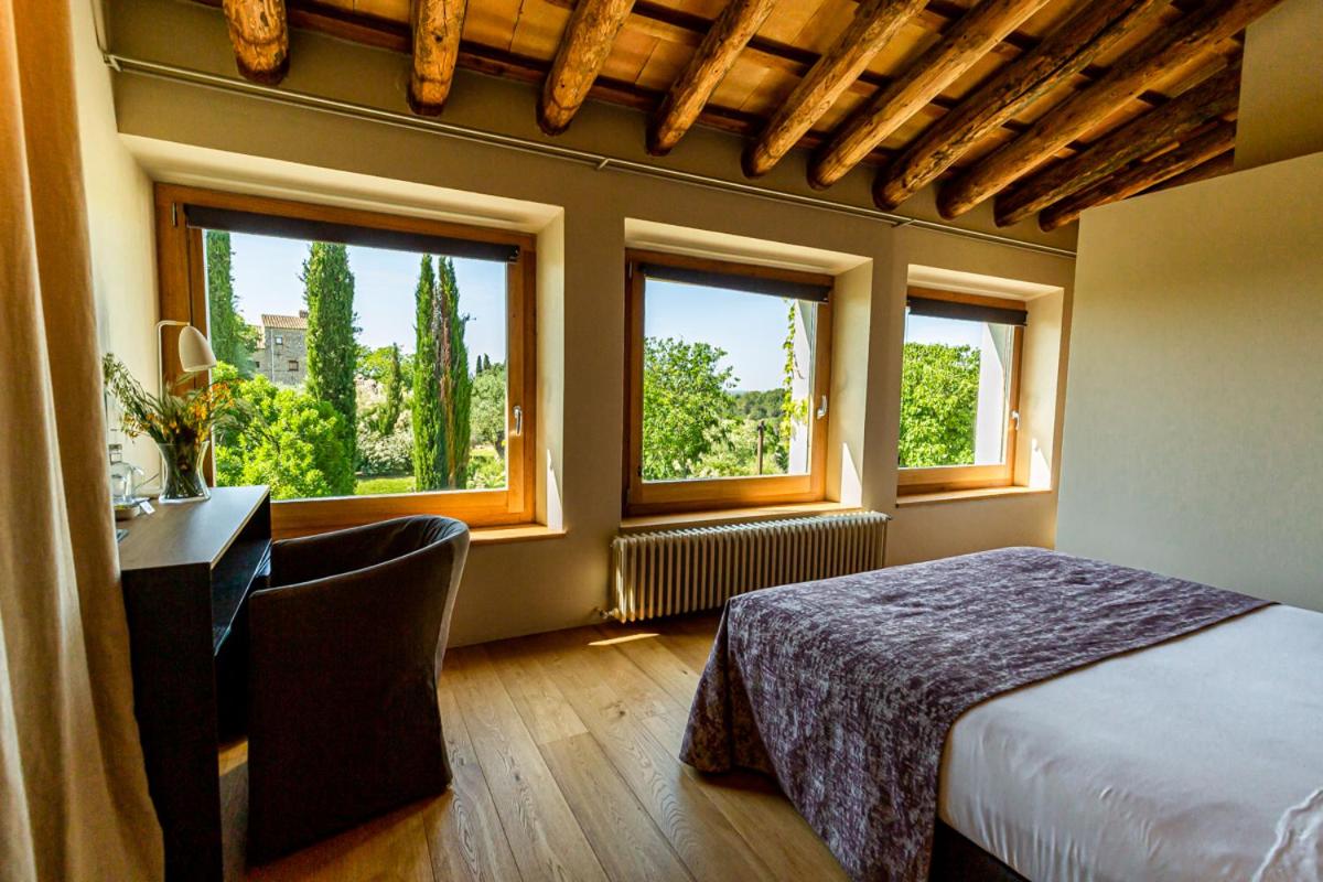 Un dormitorio con una cama y un escritorio y dos ventanas. en Hotel Mas Bosch 1526, en Avinyonet de Puigventós 78 fotos más