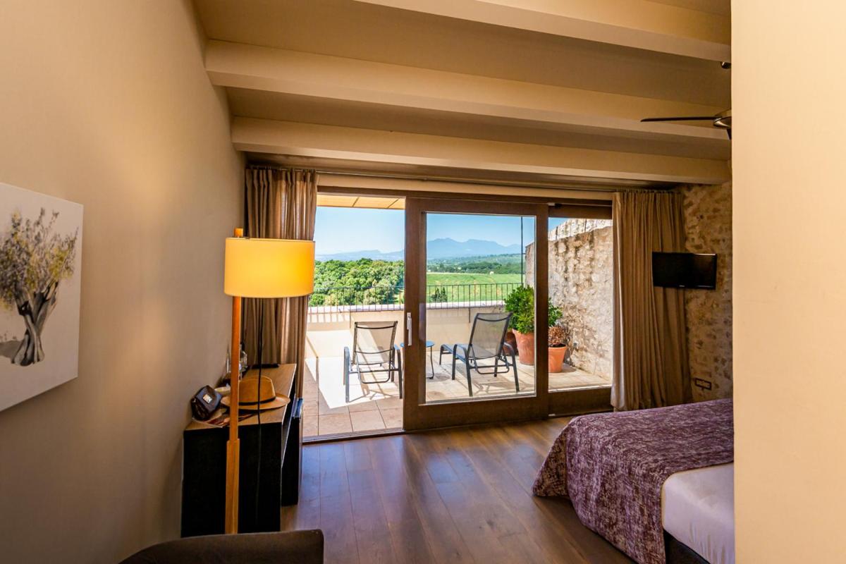 Un dormitorio con una cama y vista a un balcón. en Hotel Mas Bosch 1526, en Avinyonet de Puigventós Un dormitorio con una cama y vista a un balcón. en Hotel Mas Bosch 1526, en Avinyonet de Puigventós