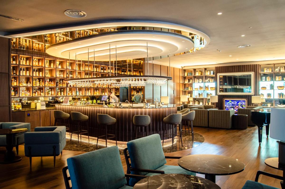 um restaurante com um bar com cadeiras e mesas em SANA Malhoa Hotel em Lisboa mais 48 fotografias