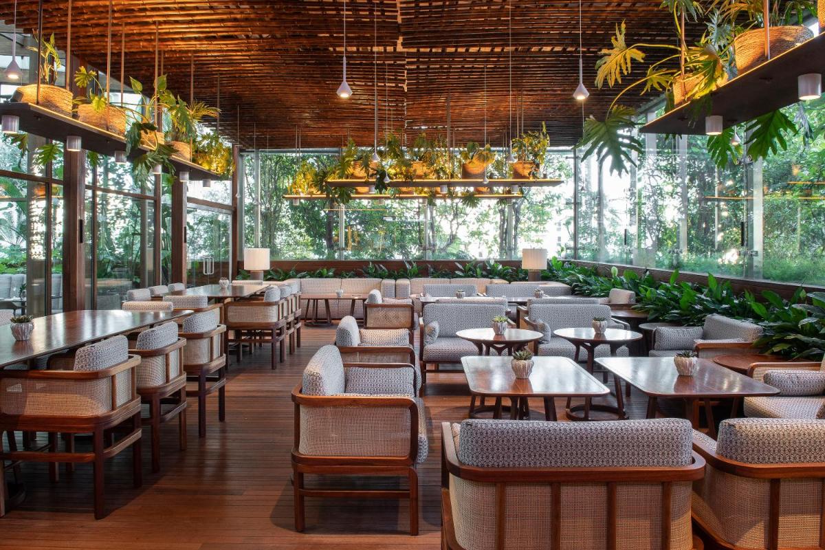 um restaurante com mesas, cadeiras e plantas em SANA Malhoa Hotel em Lisboa