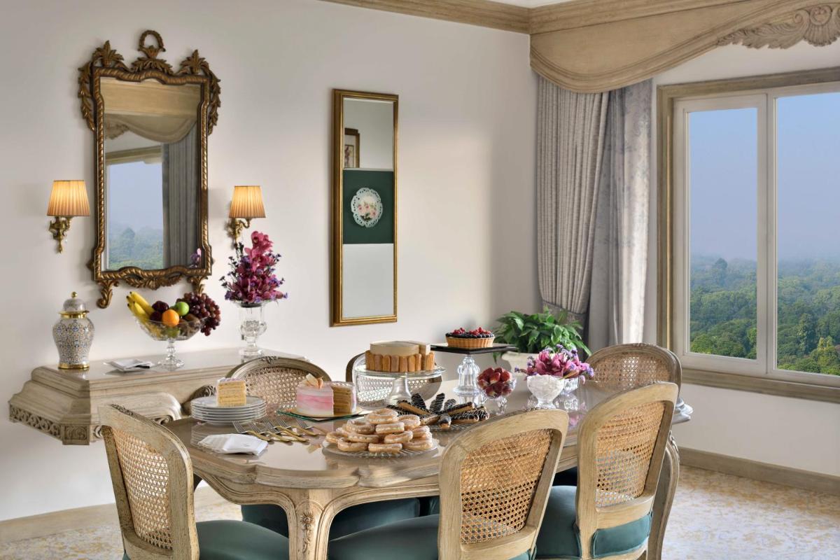 a dining room with a table with chairs and a mirror at Taj Mahal, New Delhi in New Delhi