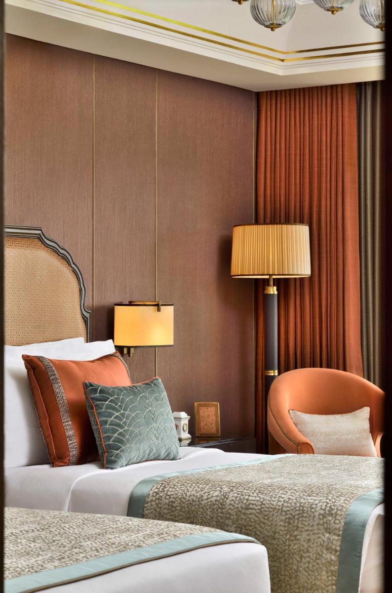 a hotel room with two beds and a chair at Taj Mahal, New Delhi in New Delhi