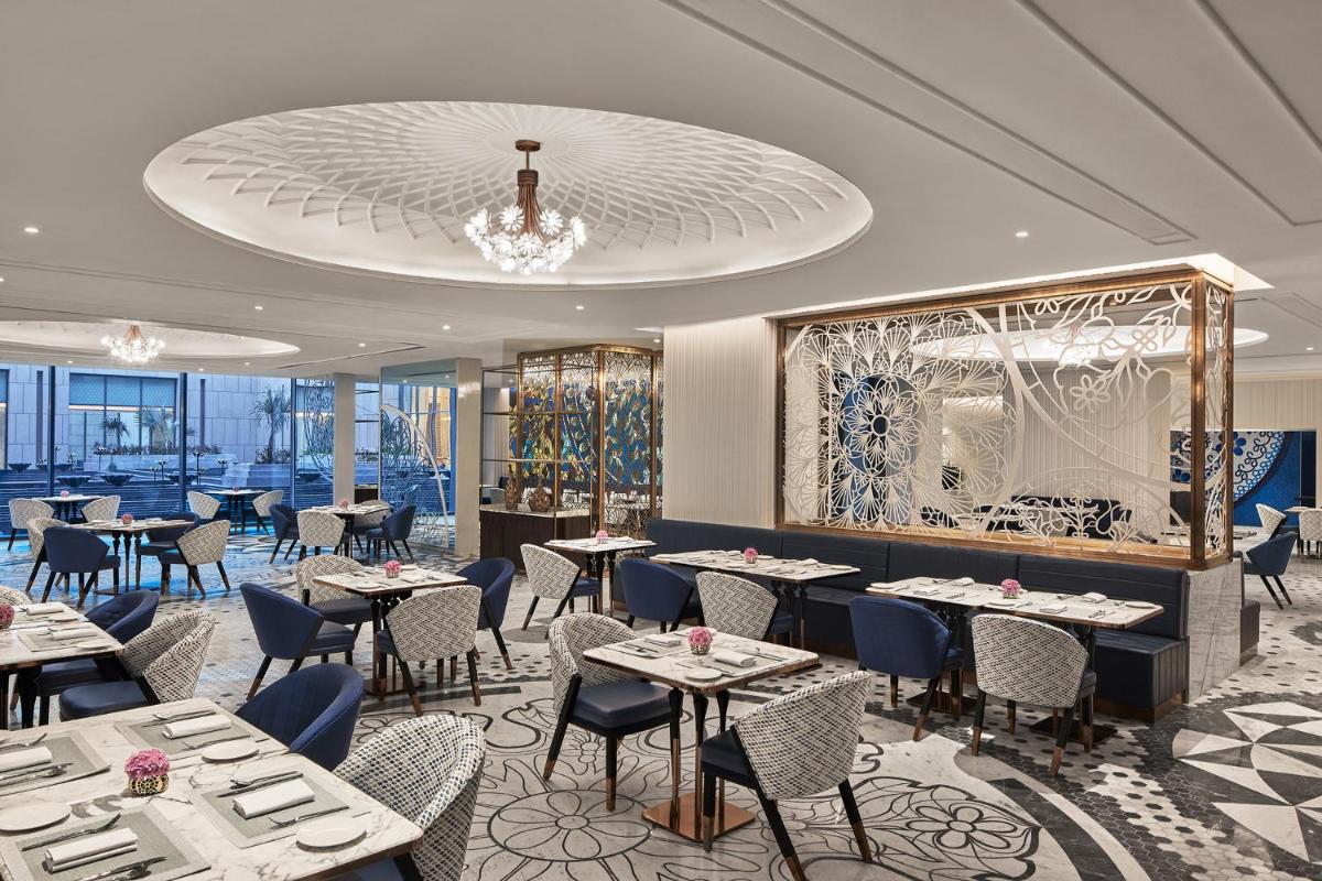 a restaurant with tables and chairs and a chandelier at Taj Amer, Jaipur in Jaipur