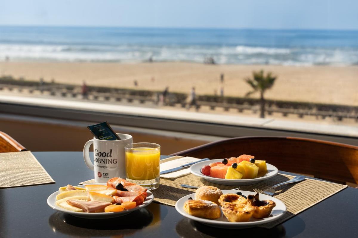 uma mesa com dois pratos de comida e vista para a praia em Dorma Praia Golfe em Espinho uma mesa com dois pratos de comida e vista para a praia em Dorma Praia Golfe em Espinho