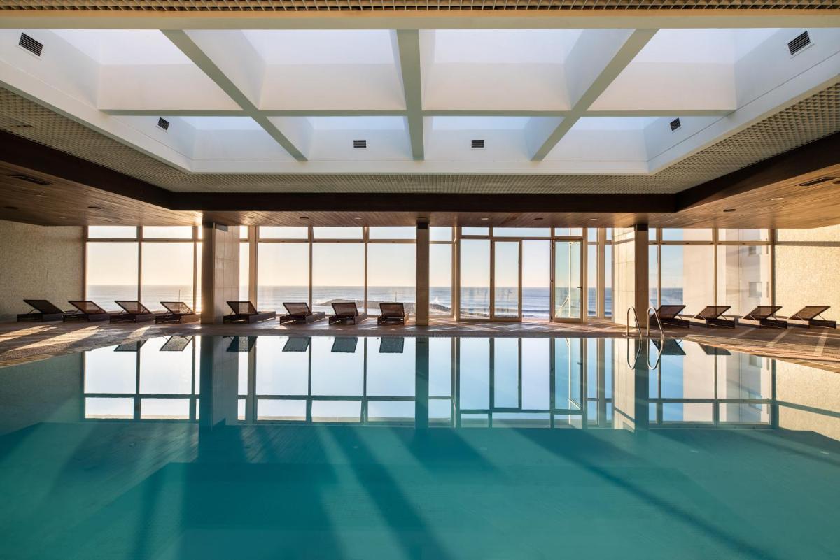 uma piscina com cadeiras em um prédio com janelas em Dorma Praia Golfe em Espinho uma piscina com cadeiras em um prédio com janelas em Dorma Praia Golfe em Espinho