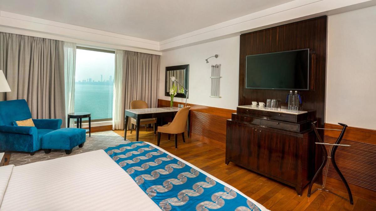 a living room with a television and a blue couch at InterContinental Marine Drive Mumbai by IHG in Mumbai
