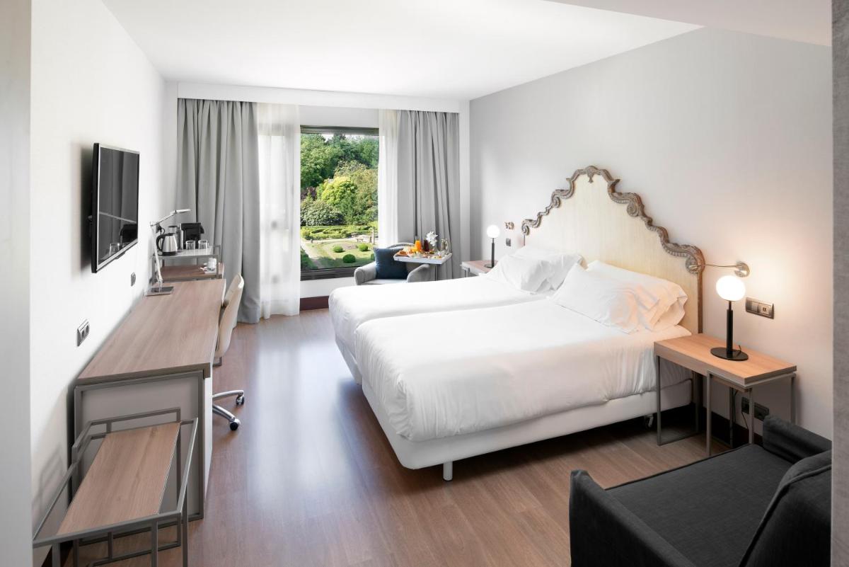 Un dormitorio con una gran cama blanca y un televisor. en Palacio de Aviles Affiliated By Melia, en Avilés