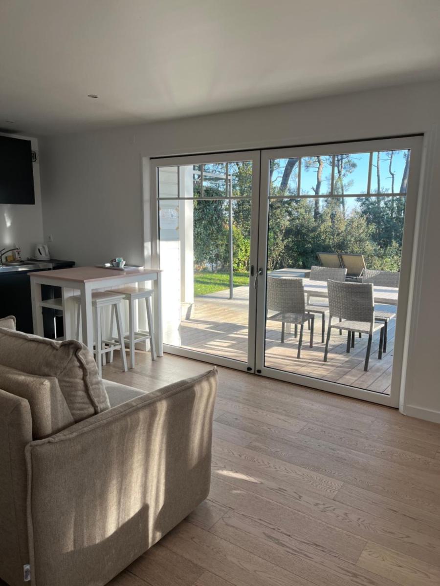 un salon avec un canapé et une porte coulissante en verre dans l'établissement La Villa Bel Ange Hotel, à Saint-Philibert