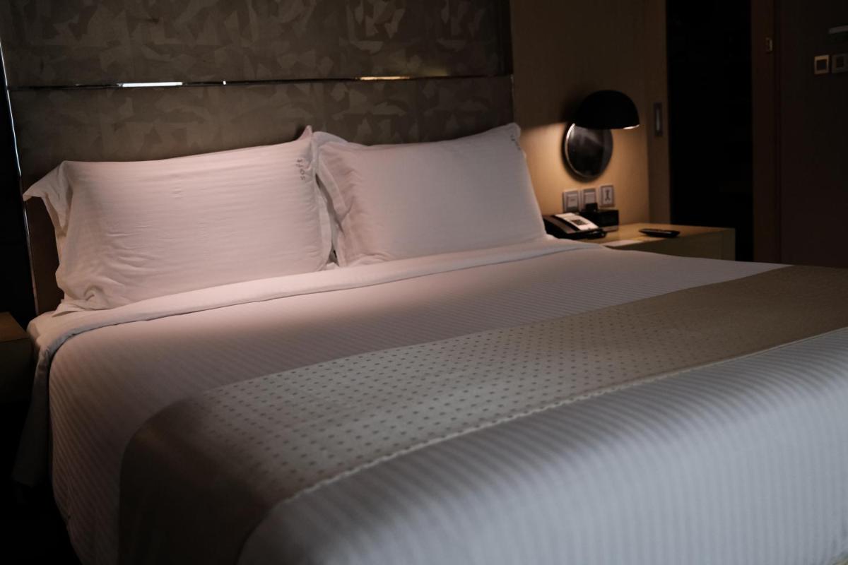 a bed with white sheets and a phone on a table at Holiday Inn New Delhi Aerocity by IHG in New Delhi