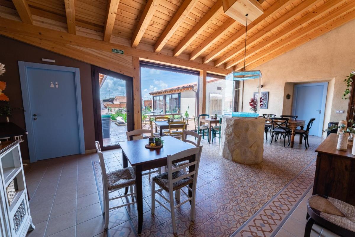Un comedor con mesa y sillas y ventanas. en El Jaraiz de Don Marciano, en Villaverde de Medina