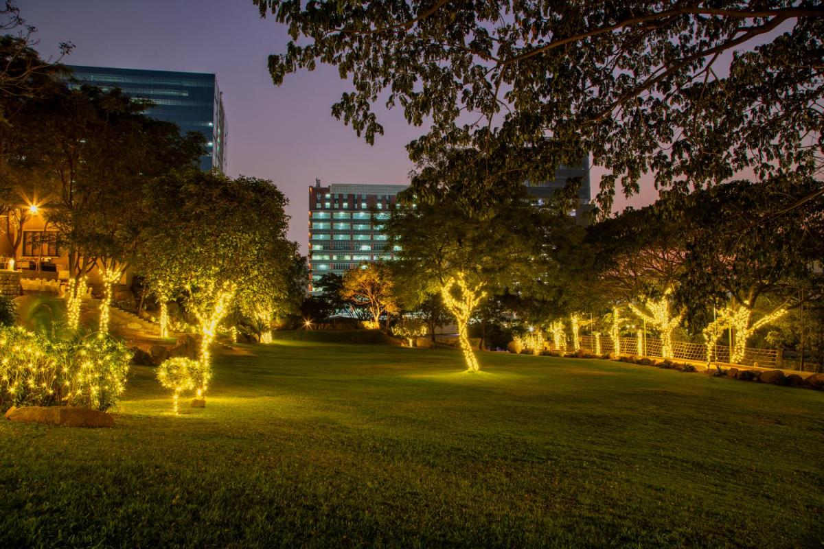 a park lit up at night with trees and lights at Hyatt Hyderabad Gachibowli in Hyderabad
