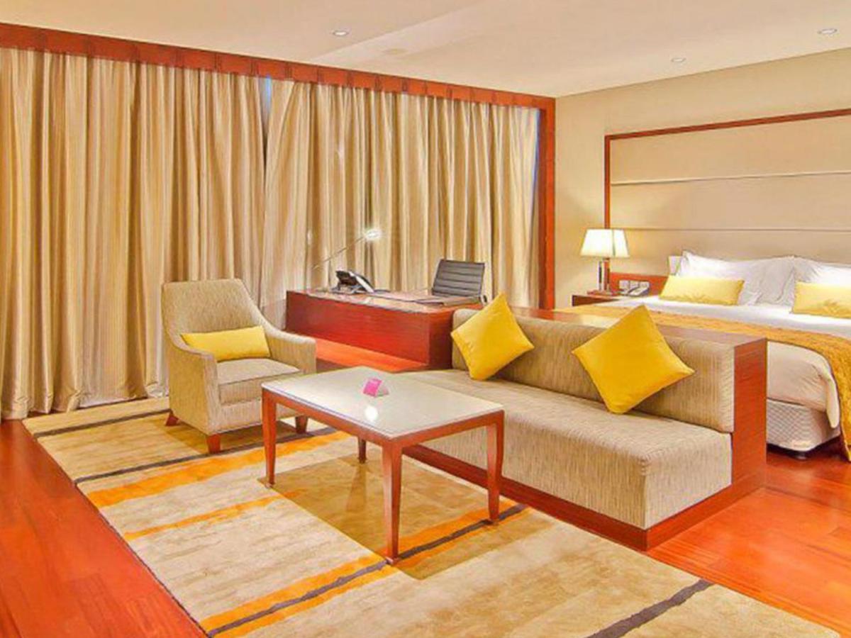 a hotel room with a bed and a couch and a table at Crowne Plaza Kochi by IHG in Cochin