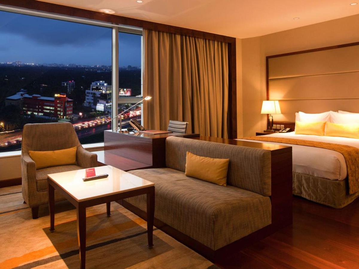 a hotel room with a bed and a couch at Crowne Plaza Kochi by IHG in Cochin