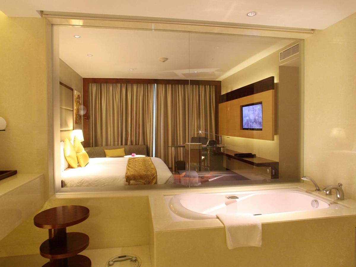 a bathroom with a tub and a bed and a mirror at Crowne Plaza Kochi by IHG in Cochin
