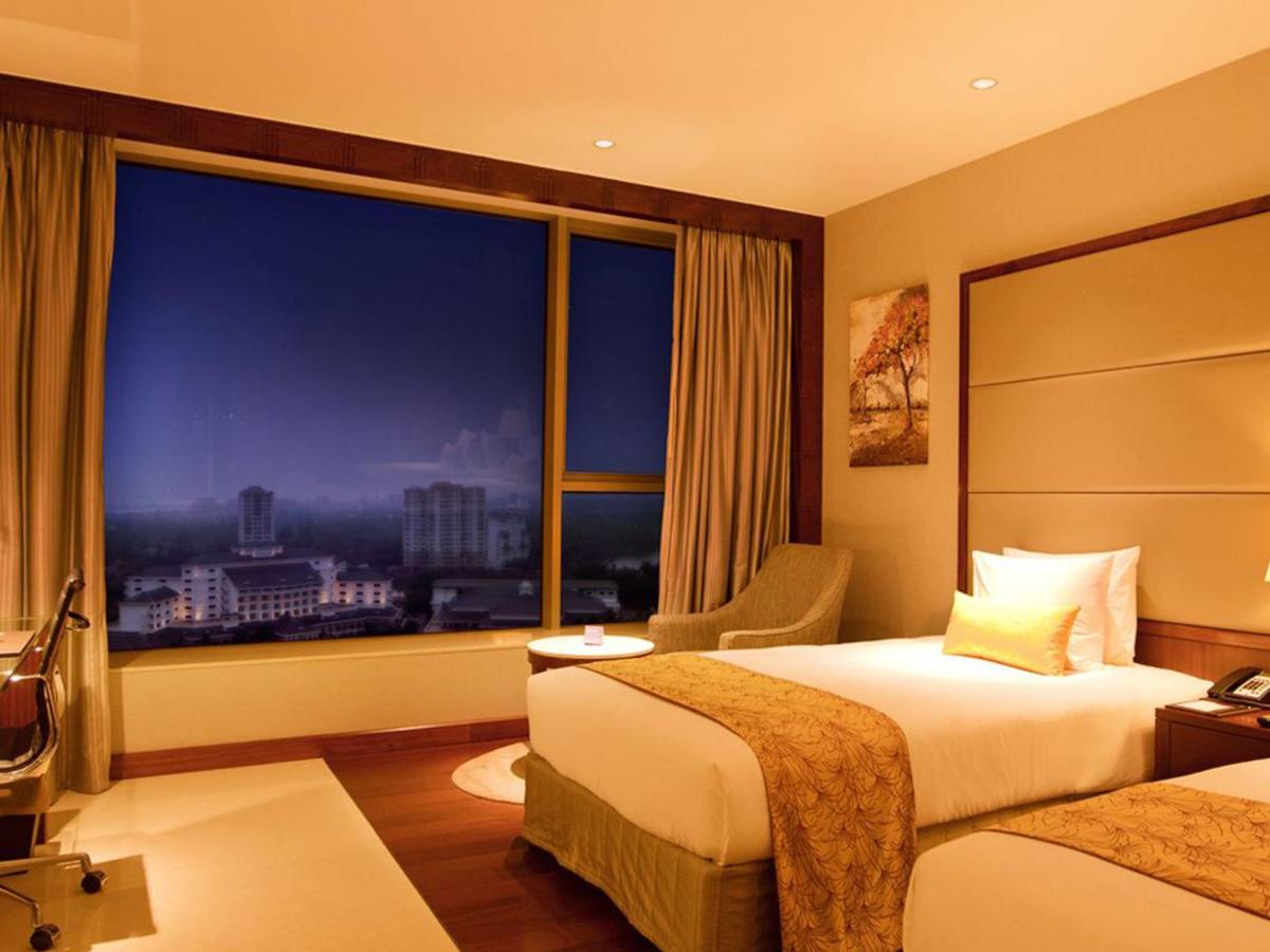 a hotel room with two beds and a large window at Crowne Plaza Kochi by IHG in Cochin