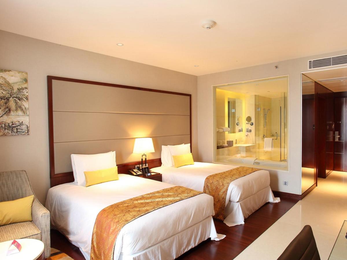a hotel room with two beds and a chair at Crowne Plaza Kochi by IHG in Cochin