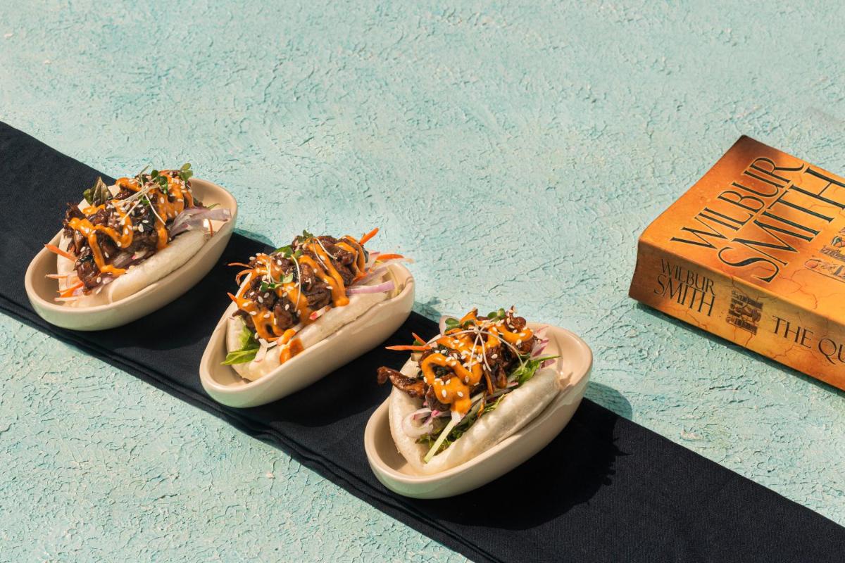 three hot dogs on plates on a table with a box at Hyatt Hyderabad Gachibowli in Hyderabad