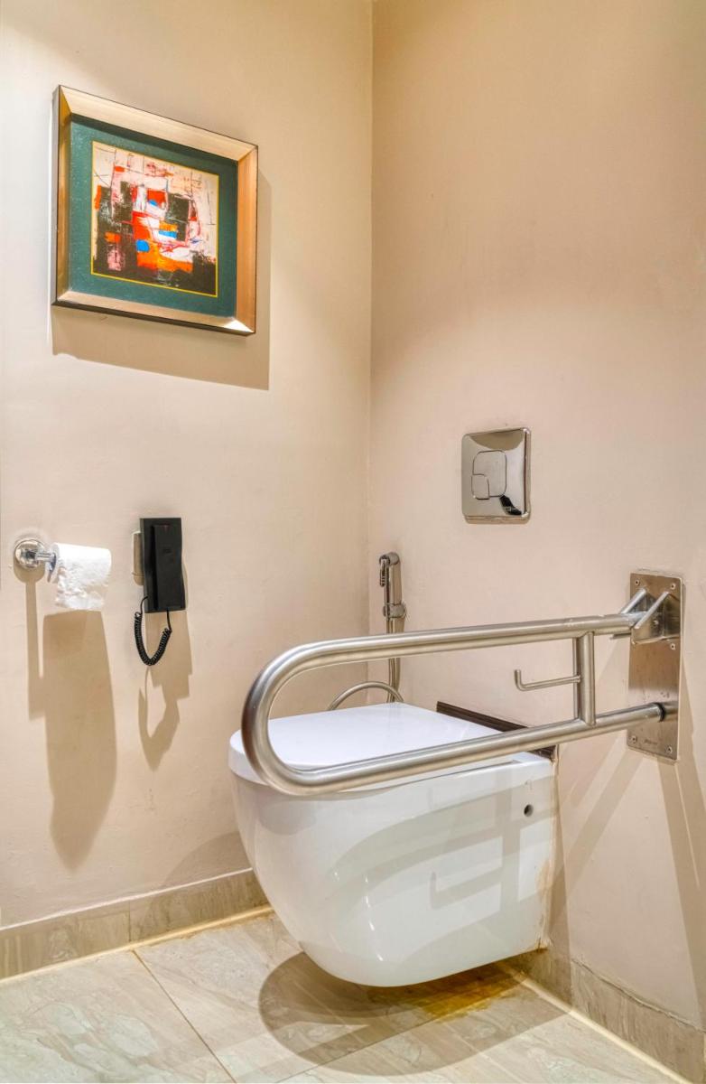 a bathroom with a toilet with a sign on the wall at Holiday Inn Kolkata Airport by IHG in Kolkata