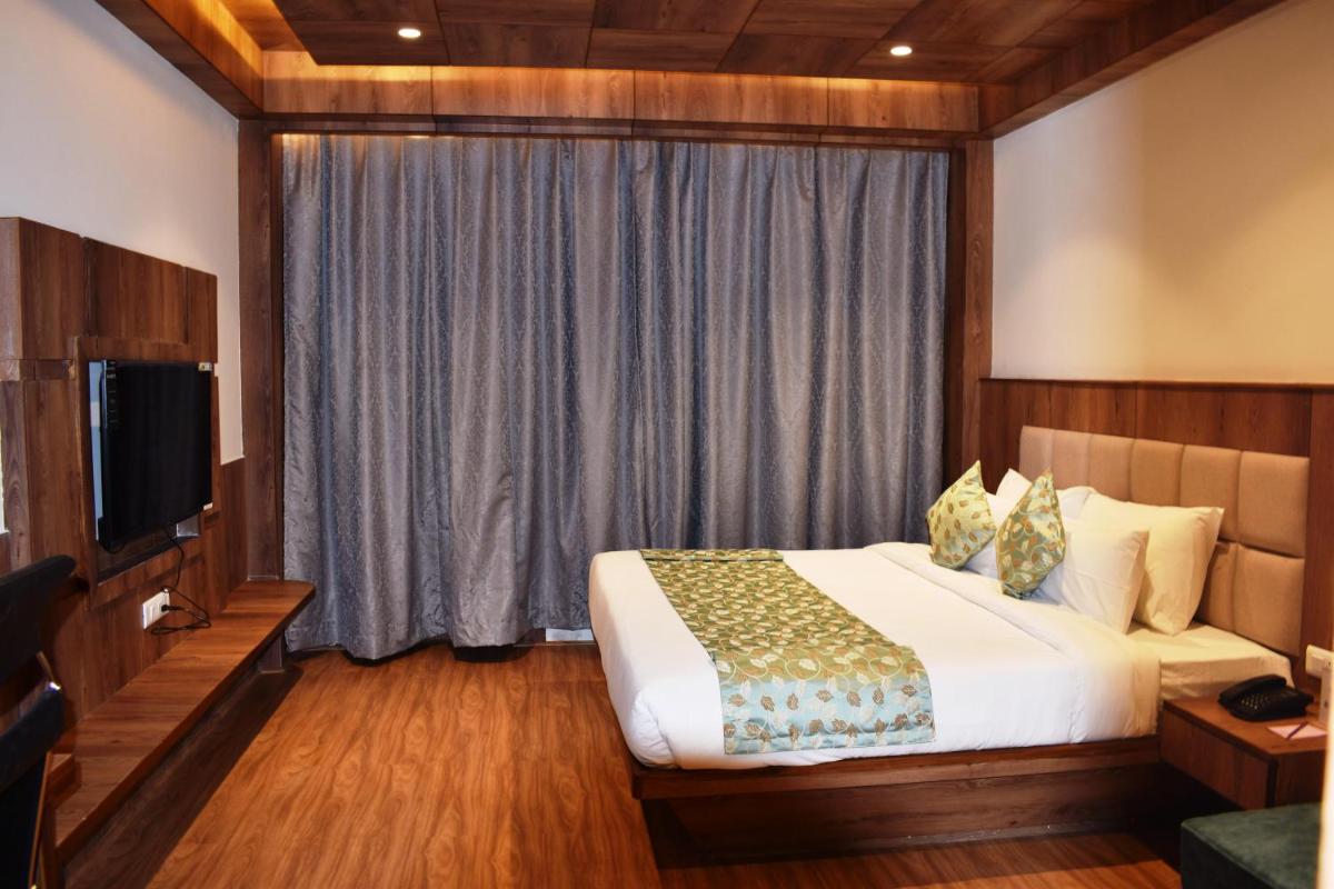 a hotel room with a bed and a television at The Orchid Manali - a Boutique Hotel in Manāli a hotel room with a bed and a television at The Orchid Manali - a Boutique Hotel in Manāli
