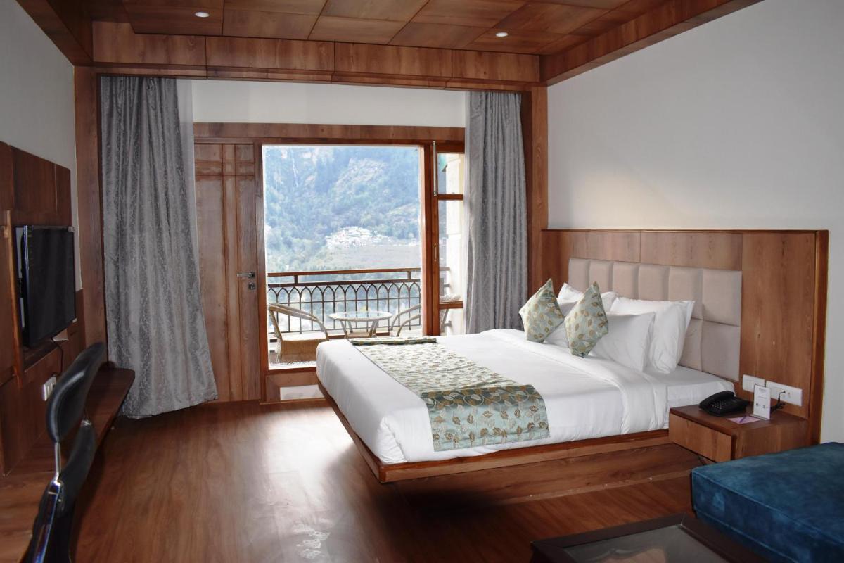 a hotel room with a bed and a balcony at The Orchid Manali - a Boutique Hotel in Manāli a hotel room with a bed and a balcony at The Orchid Manali - a Boutique Hotel in Manāli