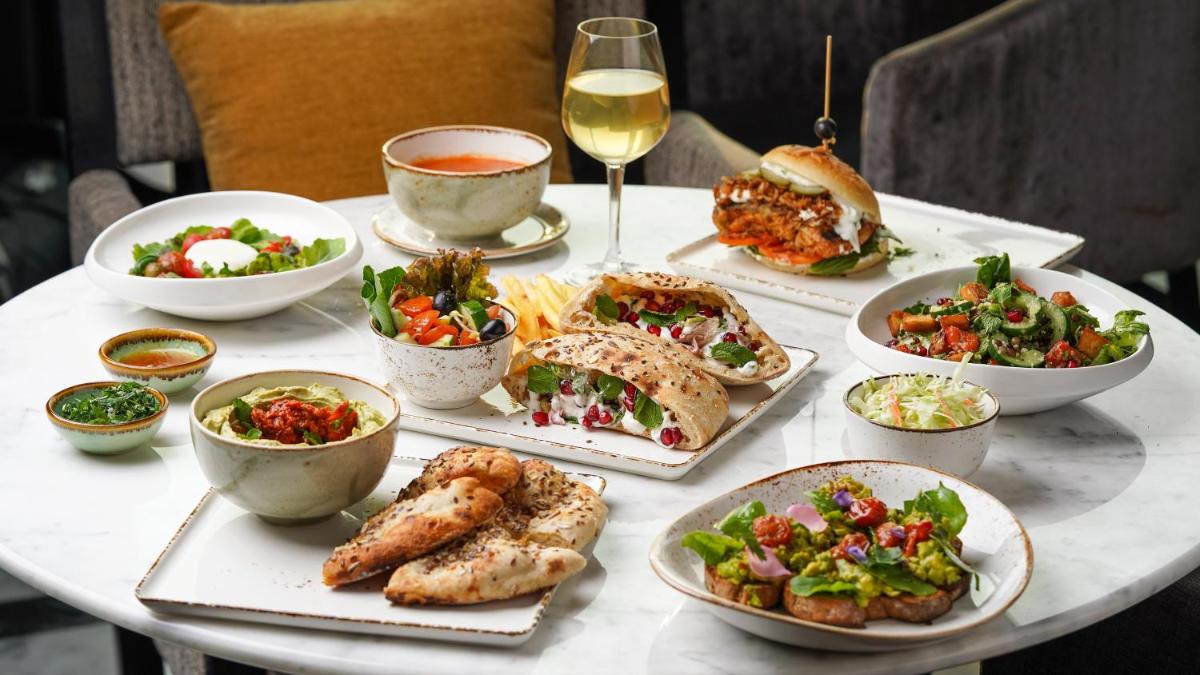 a table with dishes of food and a glass of wine at InterContinental Marine Drive Mumbai by IHG in Mumbai