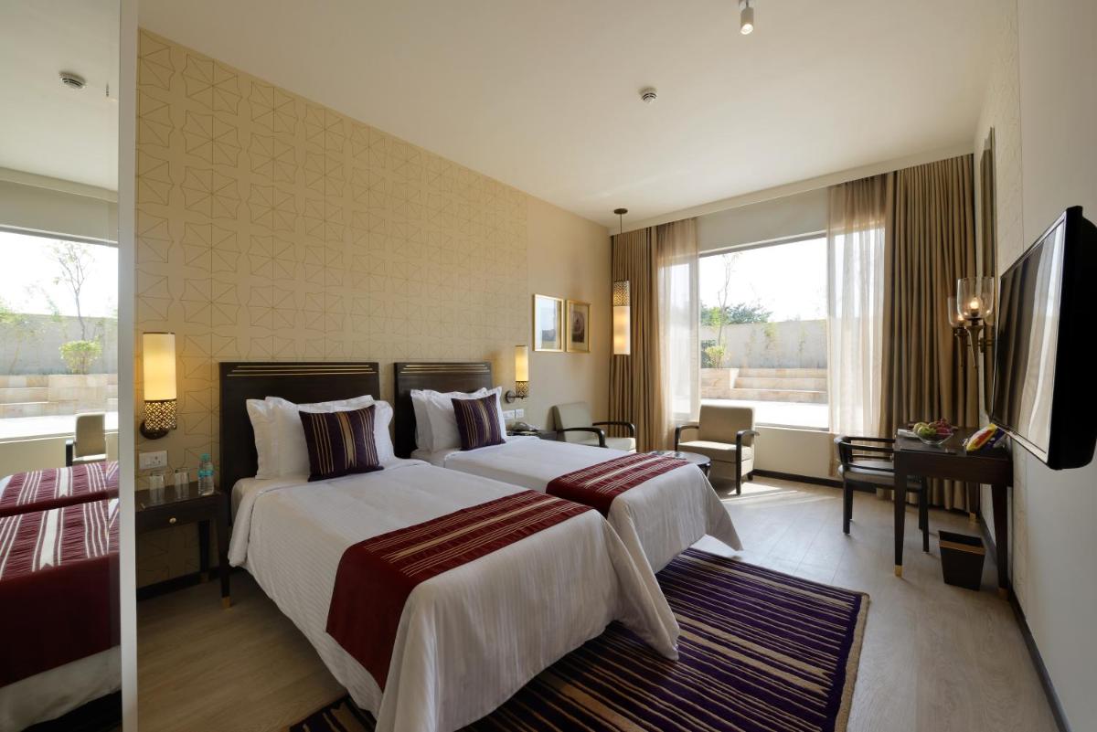 a hotel room with a large bed and a television at Marasa Sarovar Premiere in Tirupati