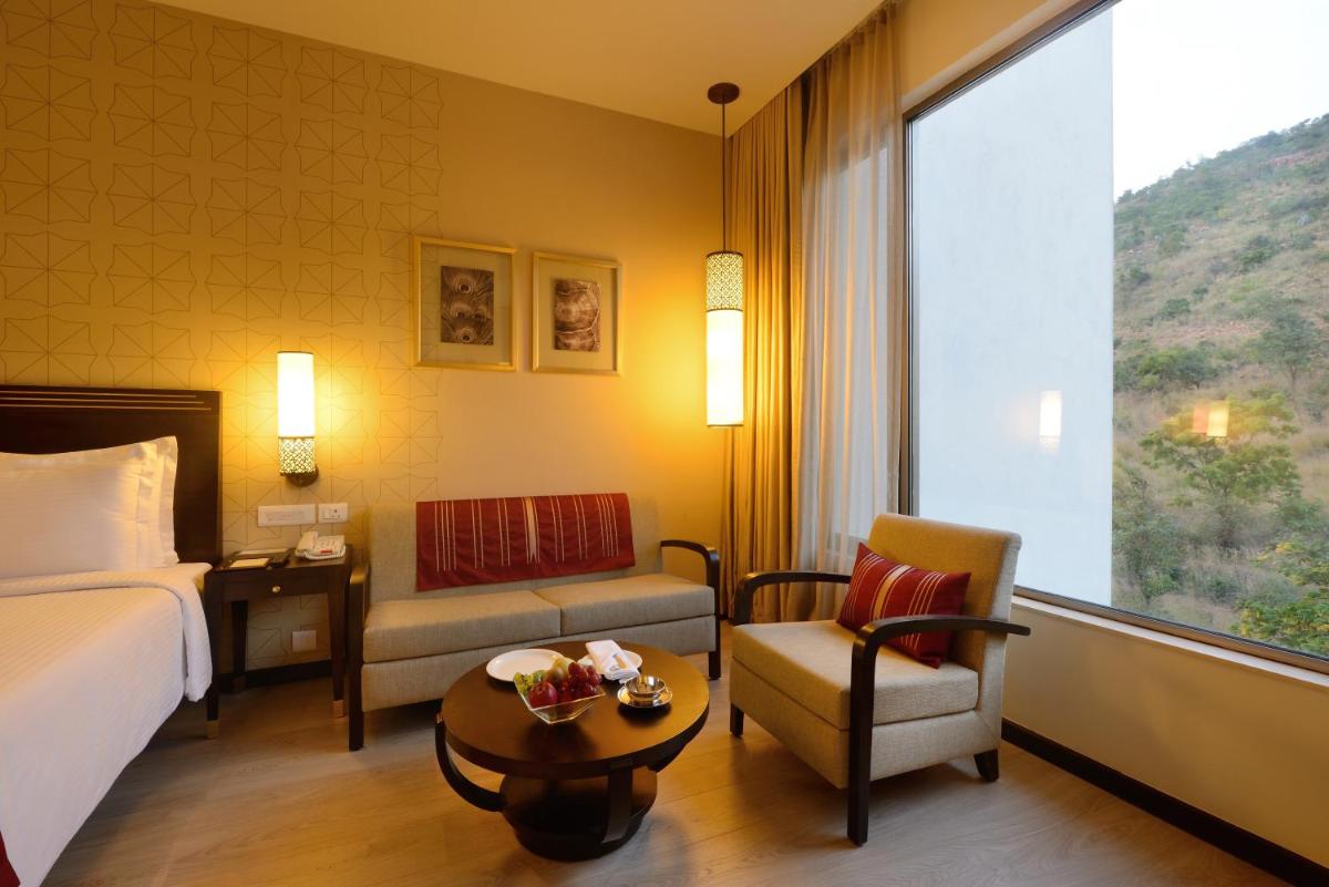 a hotel room with a bed and a chair and a window at Marasa Sarovar Premiere in Tirupati