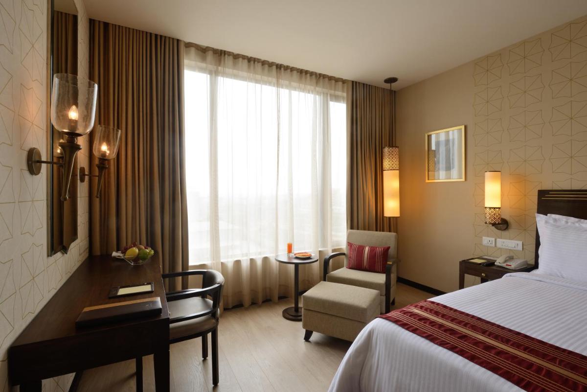 a hotel room with a bed and a chair and a window at Marasa Sarovar Premiere in Tirupati