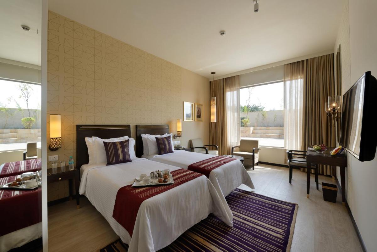 a hotel room with two beds and a flat screen tv at Marasa Sarovar Premiere in Tirupati