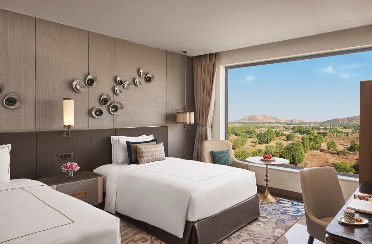 a hotel room with two beds and a large window at Taj Amer, Jaipur in Jaipur