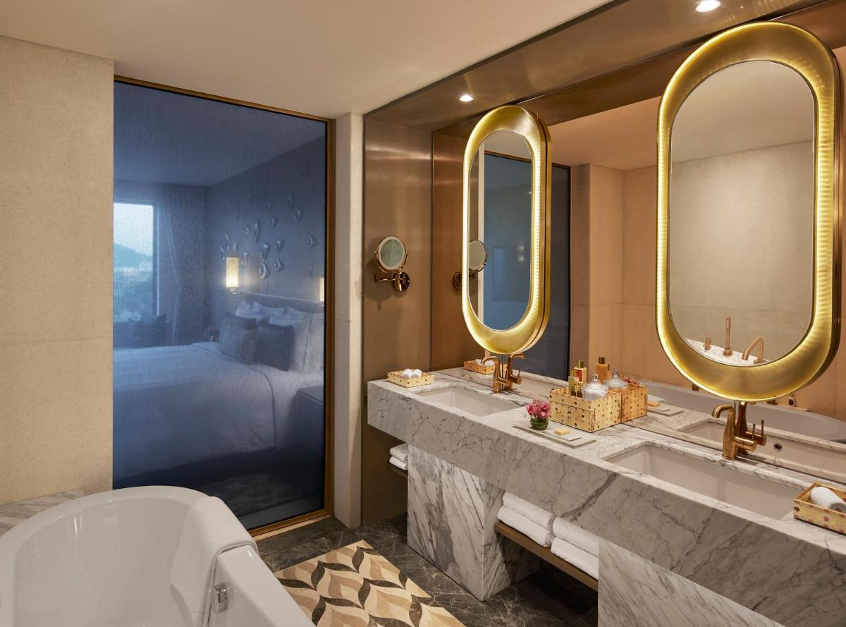 a bathroom with two sinks and two mirrors and a bed at Taj Amer, Jaipur in Jaipur