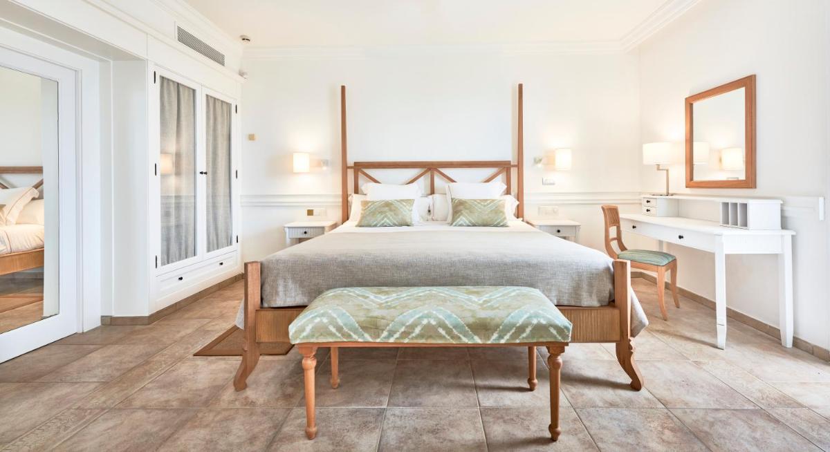 Un dormitorio con una cama, un escritorio y una silla. en Insotel Punta Prima Prestige Suites & Spa, en Punta Prima