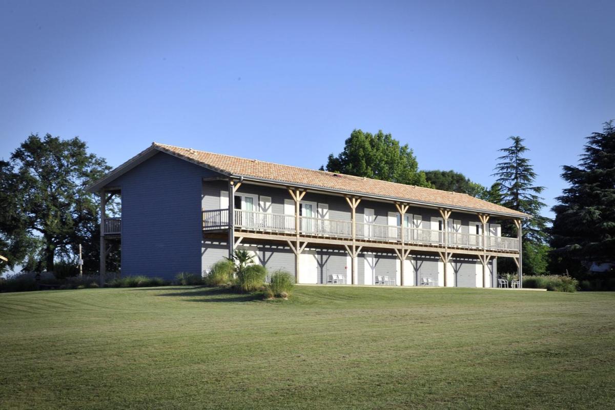 un grand bâtiment avec une grande pelouse devant lui dans l'établissement La Petite Couronne, Ecolodge & Lofts, à Saint-Cricq-Chalosse