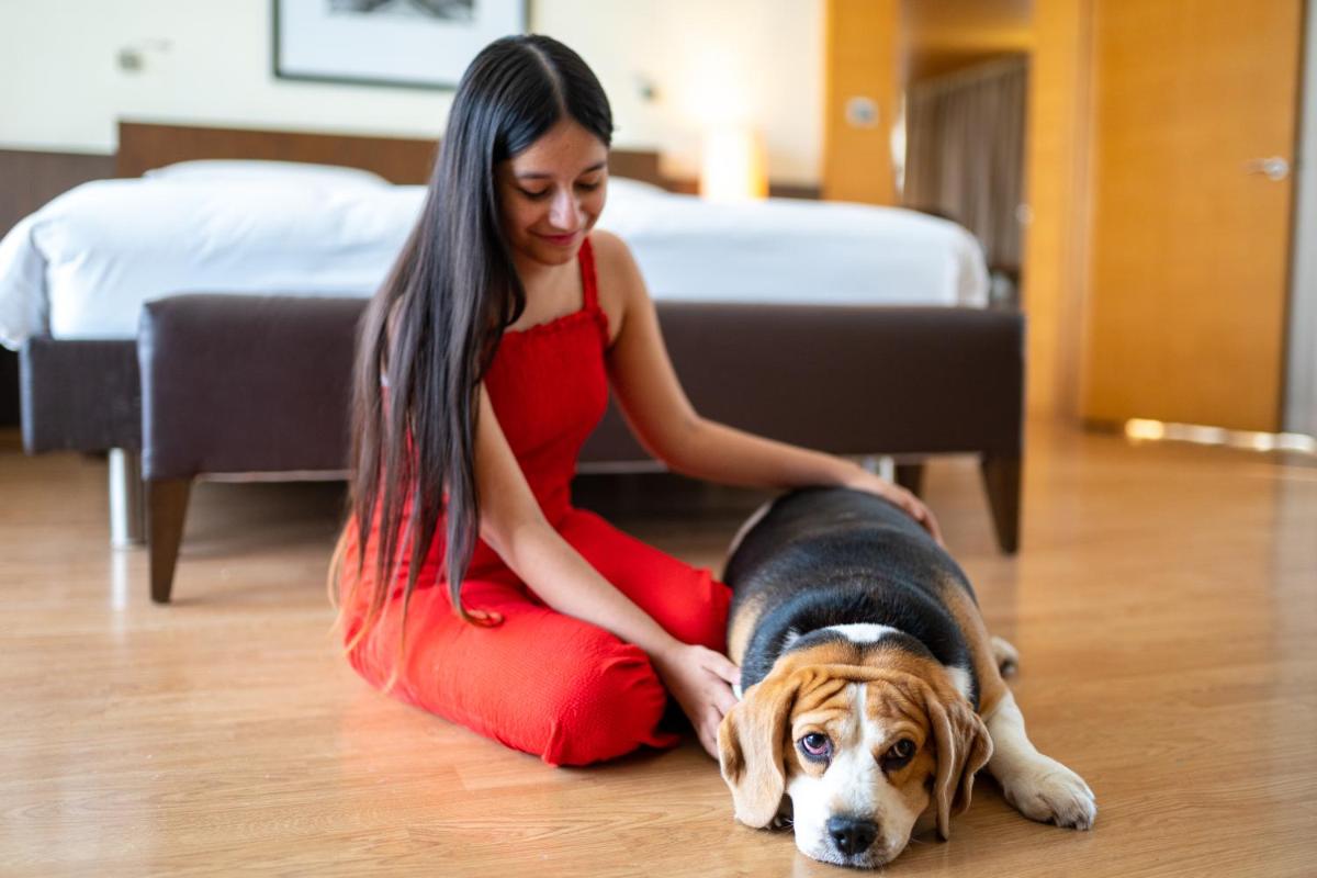 a woman in a red dress sitting on the floor with a dog at Hyatt Hyderabad Gachibowli in Hyderabad