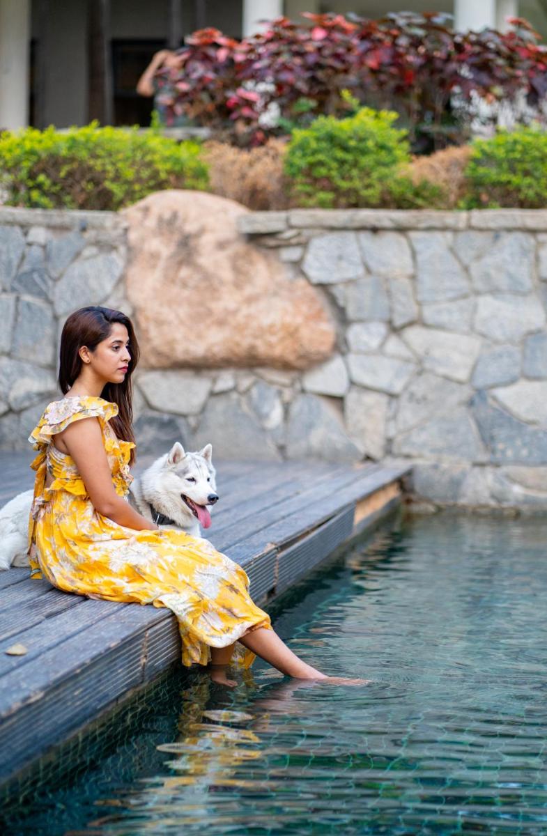 a woman sitting on a bench with a dog in the water at Hyatt Hyderabad Gachibowli in Hyderabad