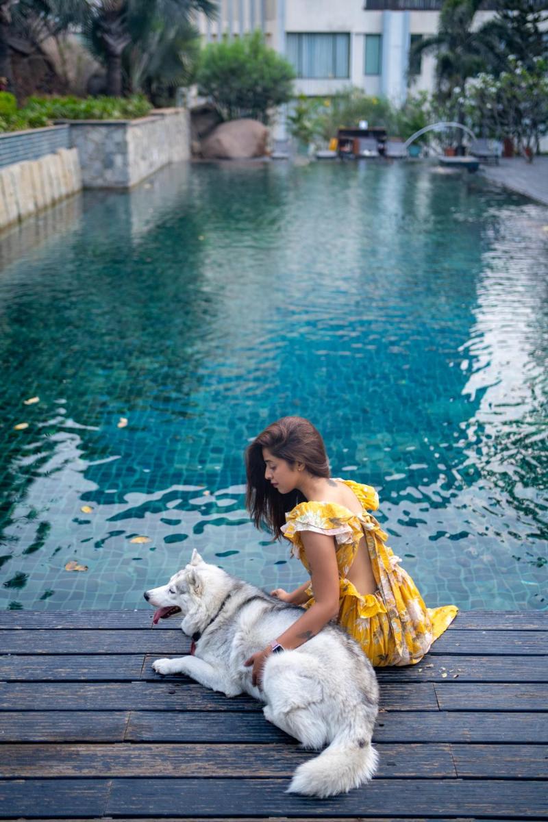a girl in a yellow dress with a dog by the water at Hyatt Hyderabad Gachibowli in Hyderabad