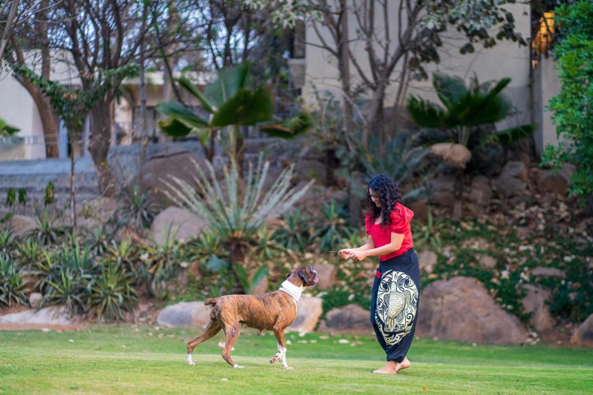 a woman playing with a dog in a park at Hyatt Hyderabad Gachibowli in Hyderabad