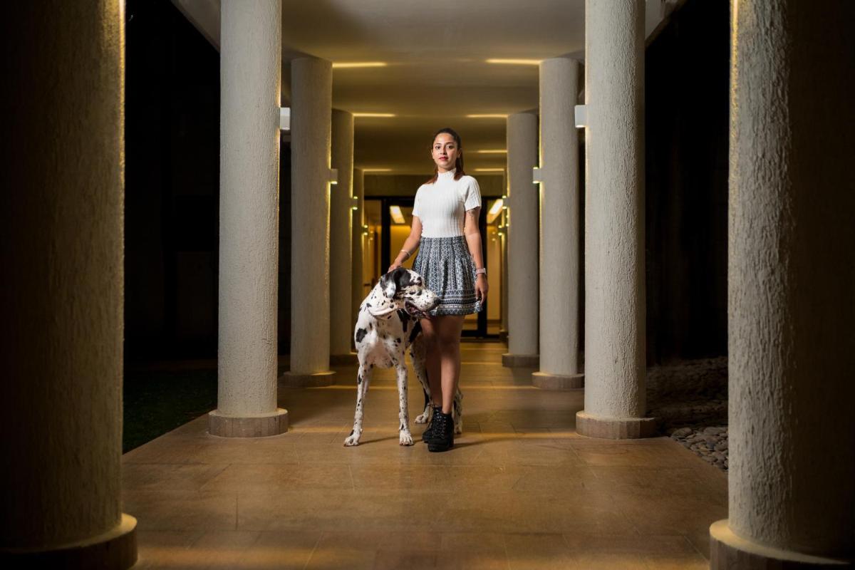 a woman walking her dog down a hallway at Hyatt Hyderabad Gachibowli in Hyderabad