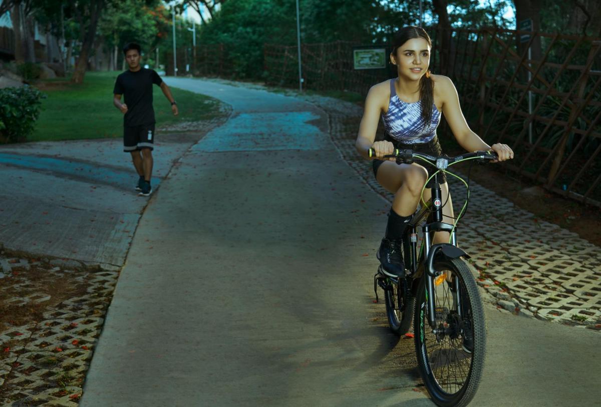 a young woman riding a bike down a street with a man at Hyatt Hyderabad Gachibowli in Hyderabad