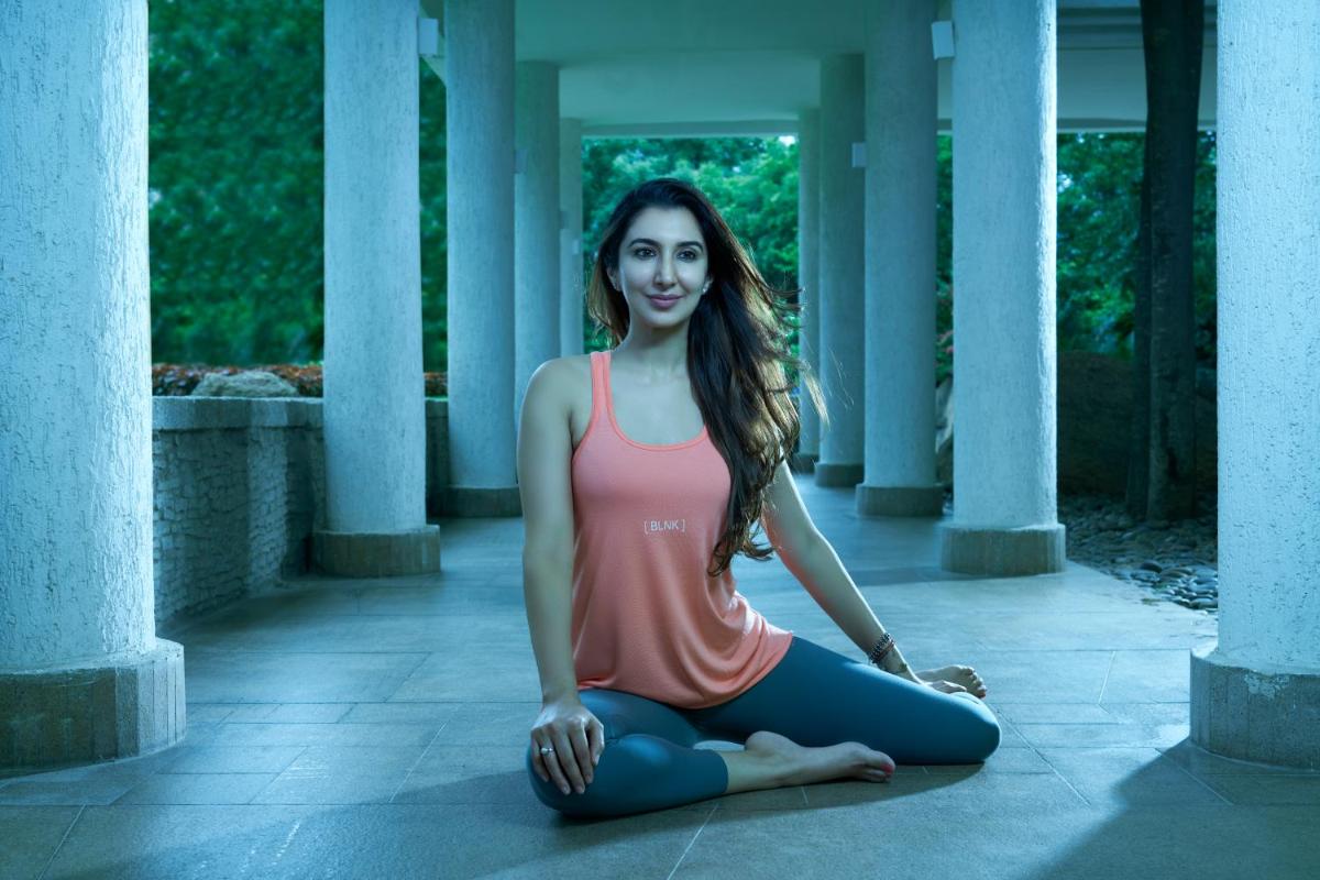 a young woman sitting on the floor in a yoga pose at Hyatt Hyderabad Gachibowli in Hyderabad