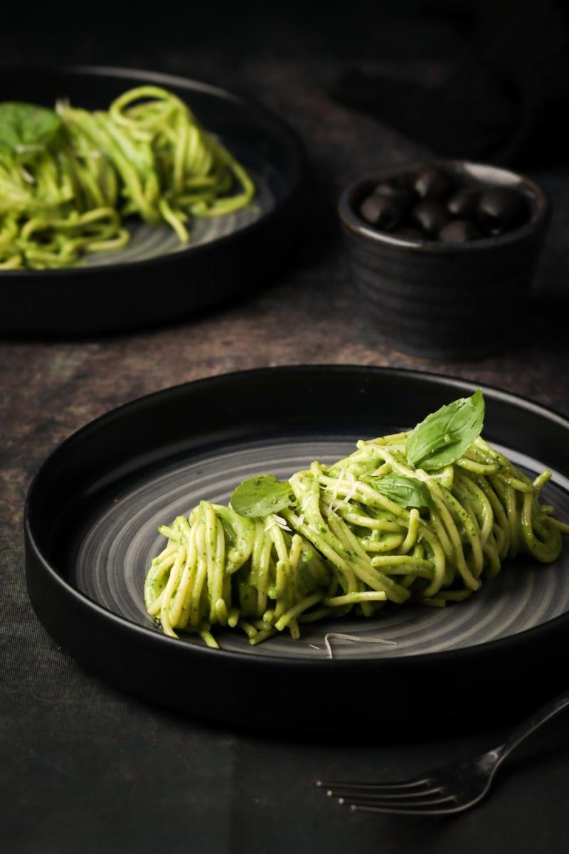 a plate of pasta with greens on a table at Hyatt Hyderabad Gachibowli in Hyderabad