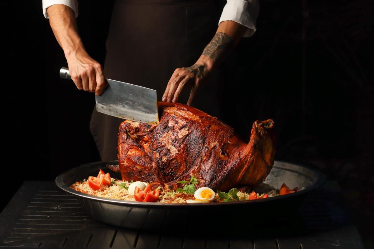 a person cutting a turkey in a pan with a knife at Hyatt Hyderabad Gachibowli in Hyderabad