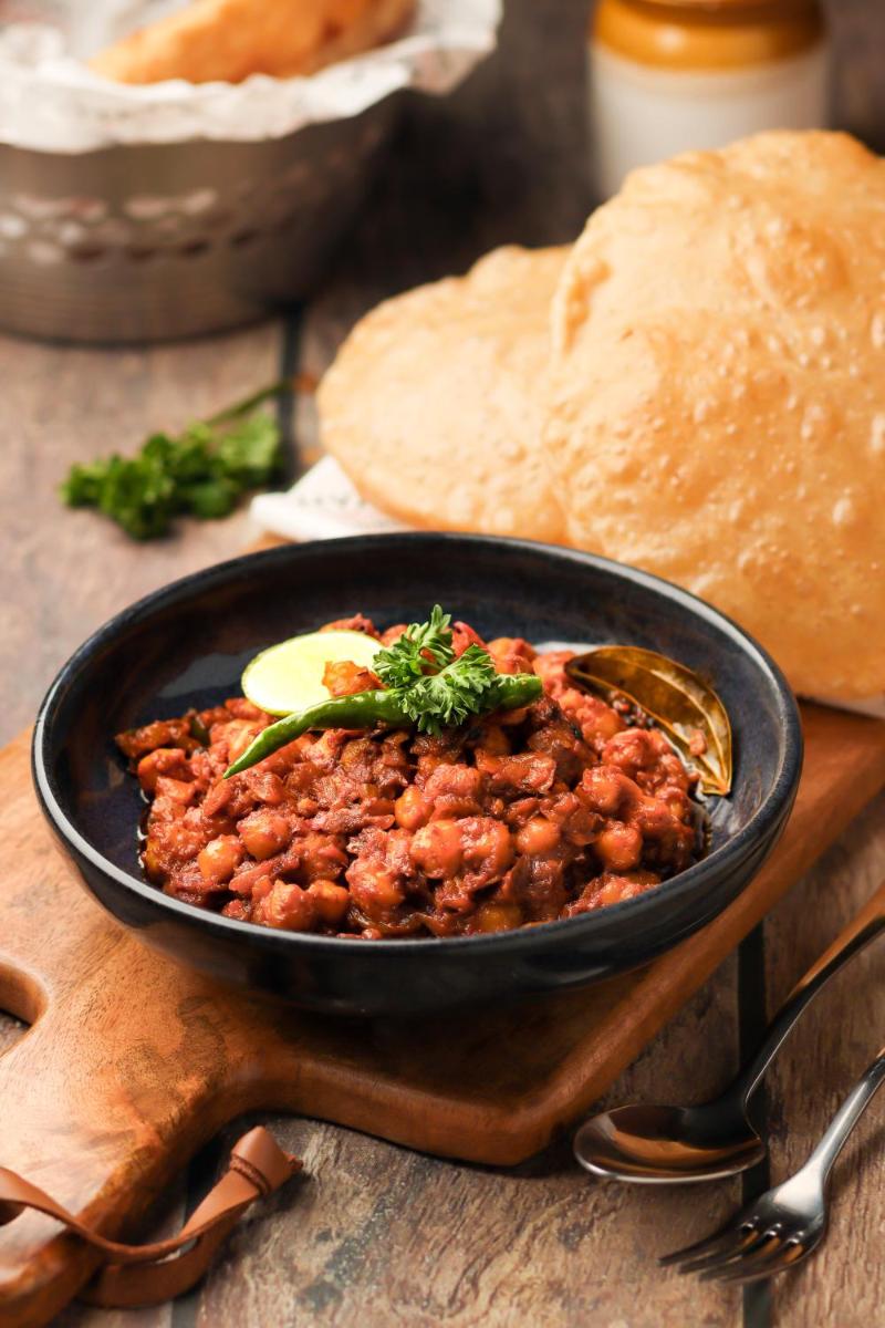 a black bowl of food on a table with bread at Hyatt Hyderabad Gachibowli in Hyderabad