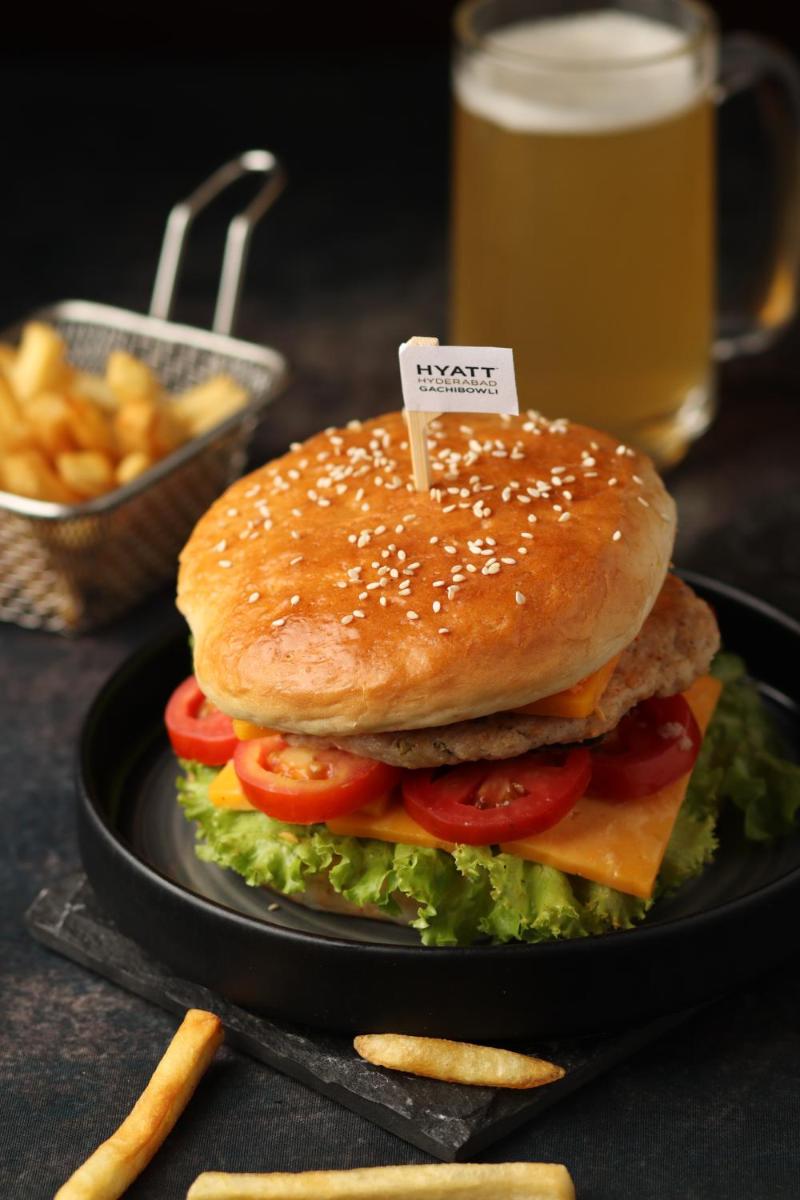 a sandwich on a plate with a glass of beer at Hyatt Hyderabad Gachibowli in Hyderabad