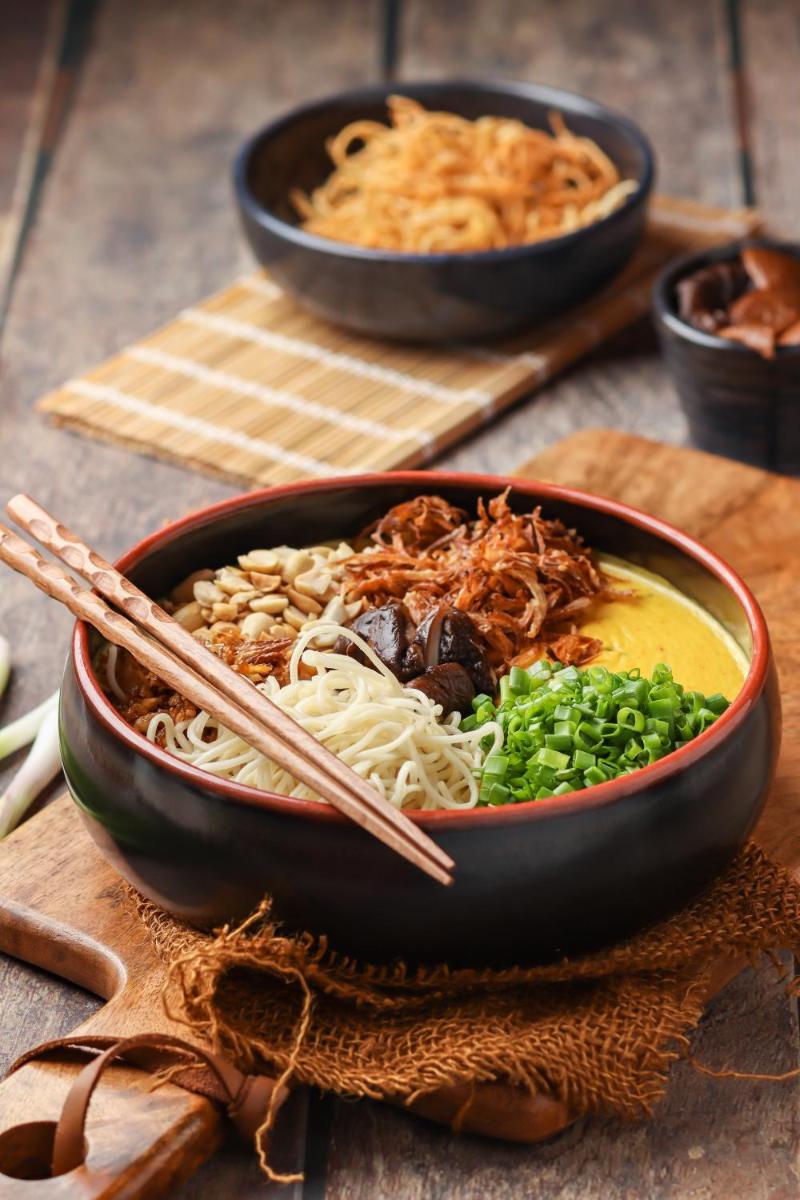 a bowl of noodles and meat with chopsticks on a table at Hyatt Hyderabad Gachibowli in Hyderabad