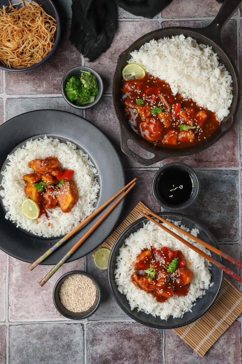 three plates of food with rice and chicken and chopsticks at Hyatt Hyderabad Gachibowli in Hyderabad